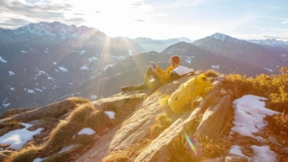 Mann auf einem Felsen, der waehrend seiner Wanderung eine Pause macht und sich entspannt, dient als Symbolbild für die Themen Anlegen und Kassenobligation.